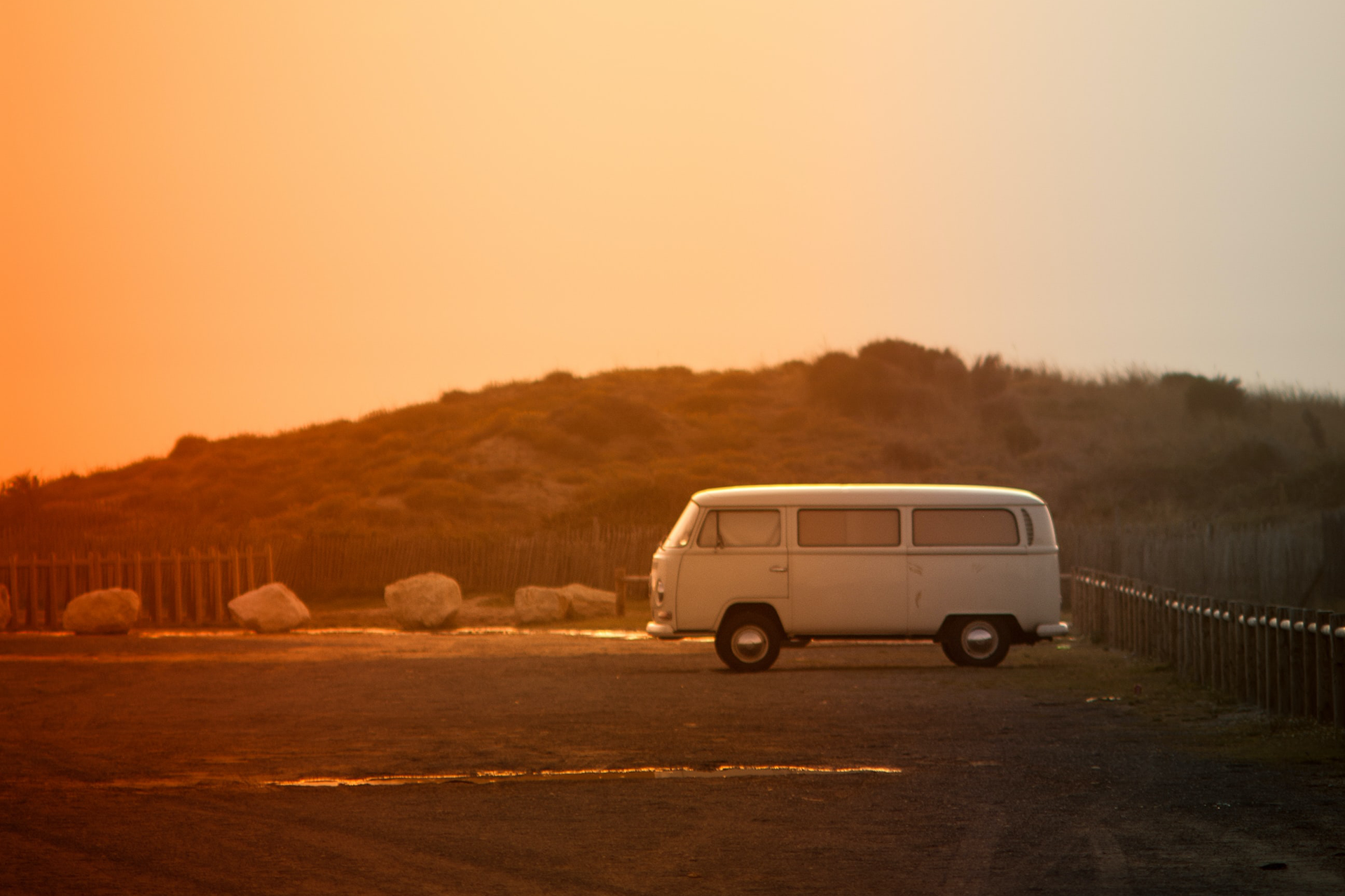 Retro campervan in de duinen tijdens zonsondergang